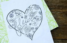 a card with the word love written on it and a heart drawn in floral designs