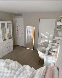 a bedroom with white furniture and lots of drawers