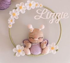 a crocheted stuffed animal sitting on top of a white table next to flowers