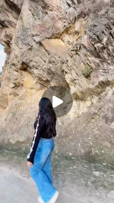 a woman walking in front of a rock formation