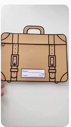 a hand holding up a piece of paper with a suitcase on the front and side