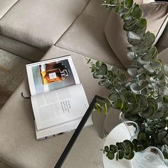 an open book sitting on top of a table next to a vase filled with plants