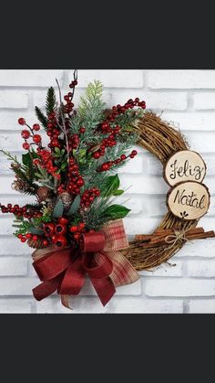 a wreath with red berries and greenery is hung on a brick wall