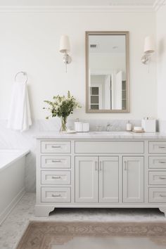 a white bathroom with two sinks and a large mirror above the bathtub is shown