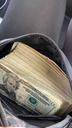 a stack of money is in the back pocket of a backpack on top of a car seat