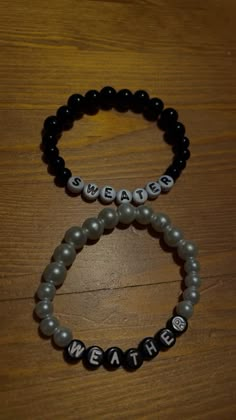 two bracelets with words on them sitting on top of a wooden table next to each other