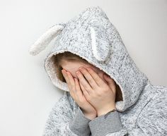 a woman covering her face with a bunny hoodie over her head and the words we need never be ashmed of our tears charles dickens