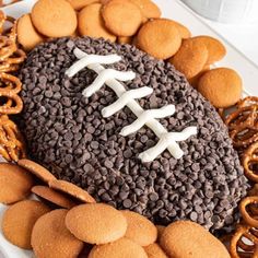 a football shaped cake surrounded by cookies and pretzels