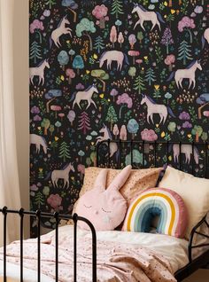 a black wallpaper with unicorns, trees and rainbows on it is next to a bed