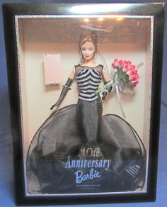 a barbie doll in a black and white dress holding a bouquet of flowers with the words 10th anniversary barbie written on it