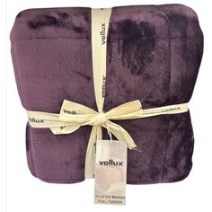 a purple blanket wrapped in yellow ribbon and tied with a white tag that says vellux