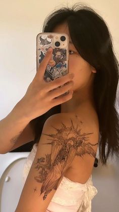 a woman taking a selfie with her cell phone in front of her face and tattoos on her arm