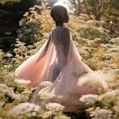 a woman is standing in the middle of some flowers