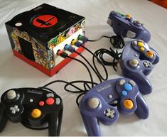 three video game controllers sitting next to each other on a white tablecloth covered surface