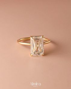 an engagement ring with a square cut diamond in the center, on a pink background