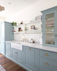 a kitchen with blue cabinets and white counter tops, gold faucet pulls on the cabinet doors