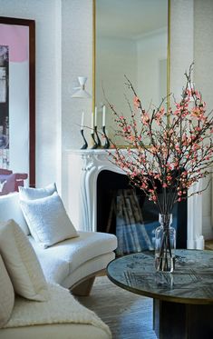 a vase filled with pink flowers sitting on top of a table next to a white couch