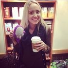 a woman holding a coffee cup in front of a bookshelf