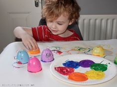 a little boy that is sitting in front of a paper plate with eggs on it