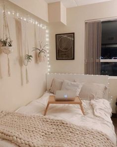 a bed with a laptop on top of it in a room filled with string lights