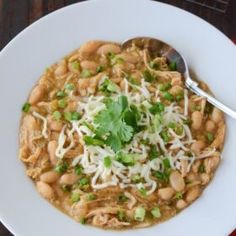 a white bowl filled with beans and green garnish on top of a wooden table