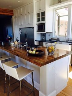 a large kitchen island with two stools next to it and a bowl of fruit on the counter