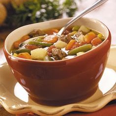 a brown bowl filled with stew and vegetables