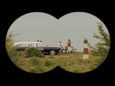 two people standing next to a car near the ocean