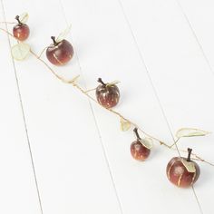 three cherries are hanging from a string on a white background with leaves and twigs