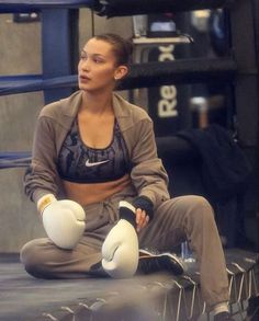 a woman sitting on the ground with boxing gloves