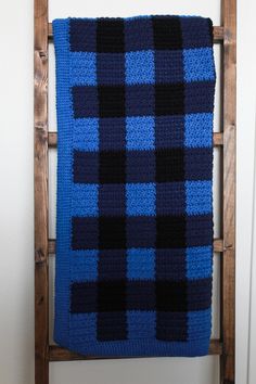 a blue and black blanket sitting on top of a wooden chair next to a white wall