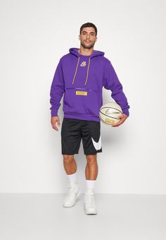 a man holding a basketball while wearing a purple hoodie