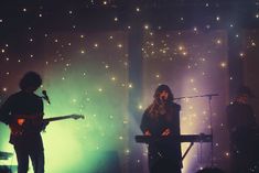 two people playing instruments on stage in front of lights and sound equipment with microphones