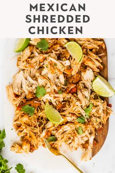 mexican shredded chicken on a white plate with limes and cilantro