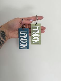 a hand holding two wooden tags that say happy halloween