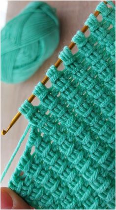 someone is stitching the stitches on their green crochet blanket with two knitting needles