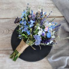 a bouquet of wildflowers and lavender on a black plate with a gray linen