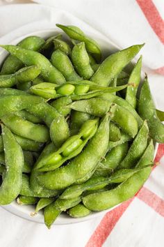 a white bowl filled with green beans on top of a table