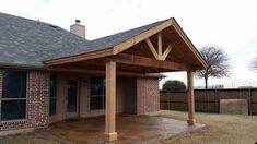 a covered patio in front of a brick house