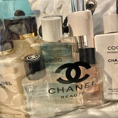 an assortment of chanel products displayed on a white sheeted surface with water bottle in the background