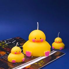 three little yellow rubber ducks sitting on top of a book next to each other,