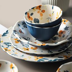 a stack of plates with blue and orange flowers on them sitting on top of a table