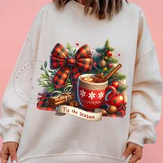 a woman wearing a christmas sweater with a mug and cinnamon on the front, holding her hands in her pockets