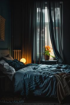 a bed sitting in front of a window next to a night stand with a lamp on it