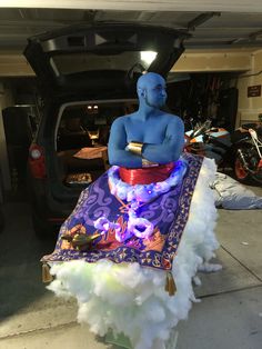 there is a blue man sitting on top of a purple blanket in the garage with his arms crossed