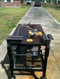 a work bench with tools on it sitting in the middle of a sidewalk next to a car