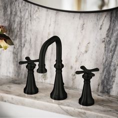 two black faucets sitting on top of a marble counter next to a mirror