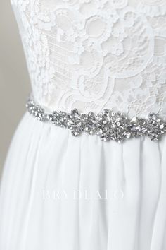 a white dress with silver beading on the waist and belt is shown in close up