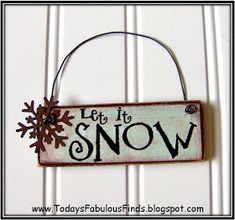 a sign that says let it snow hanging on a wall with the word'let it snow'in black and white