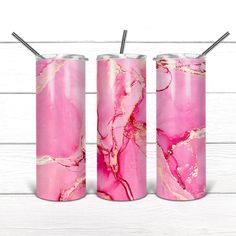 three pink marbled tumblers with straws in them on a white wood background